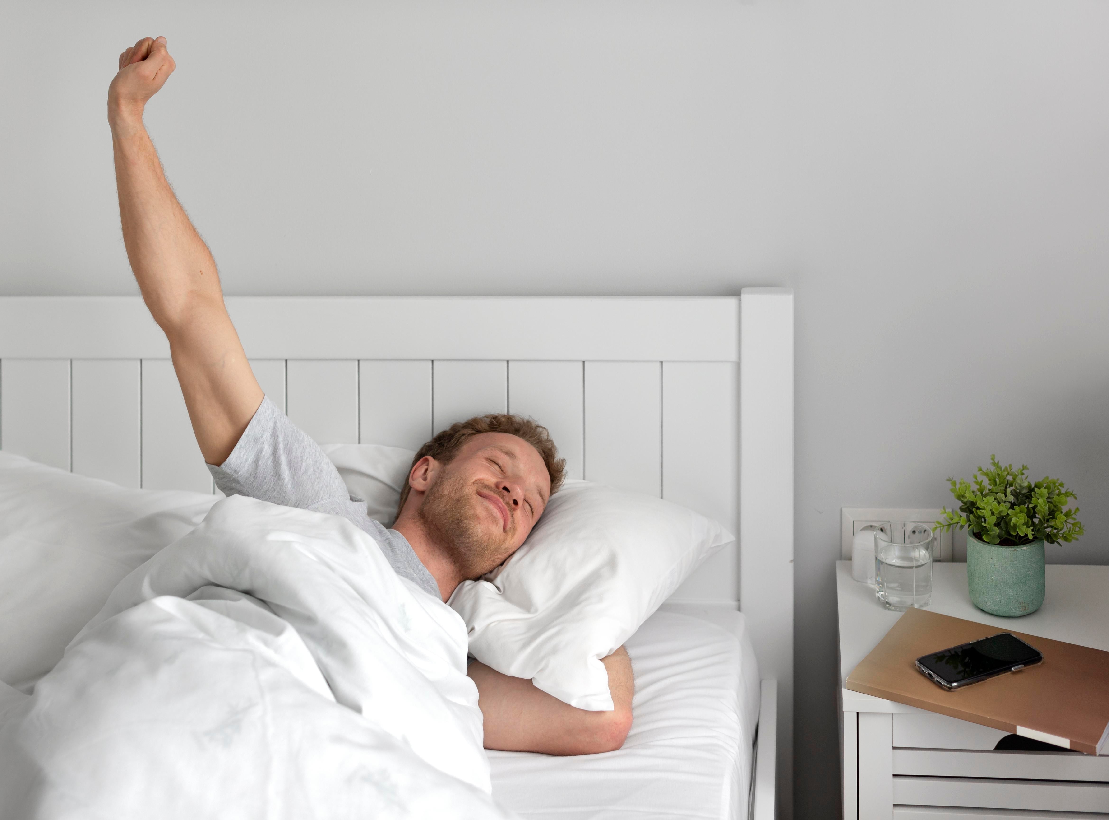 Man waking up refreshed, highlighting the importance of quality sleep for mental and physical wellbeing, as discussed by The Vitalogy Project